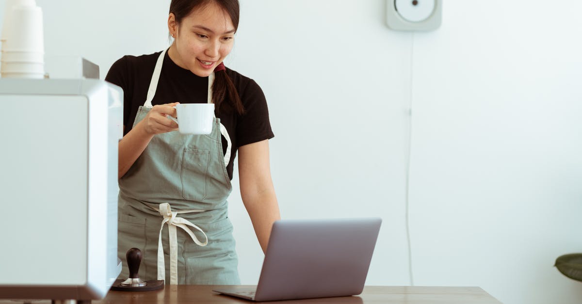 Do professional cooks use measuring cups and spoons? - Cheerful woman with cup of beverage working on laptop