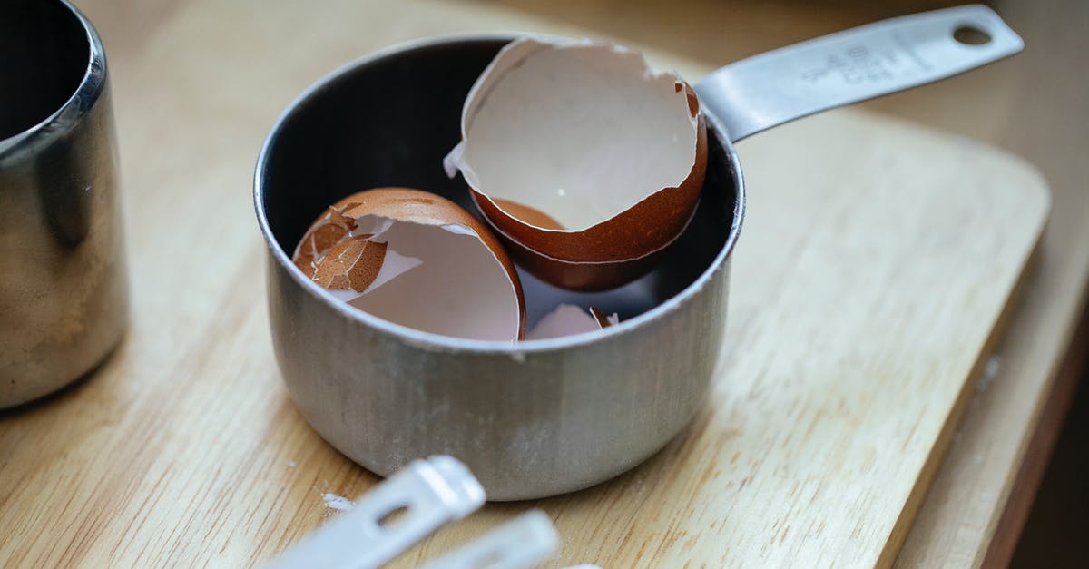 Do tomatoes or tomato pastes damage stainless steel cookware? - From above of stainless steel scoop with crashed eggshells placed on wooden table in kitchen in daylight