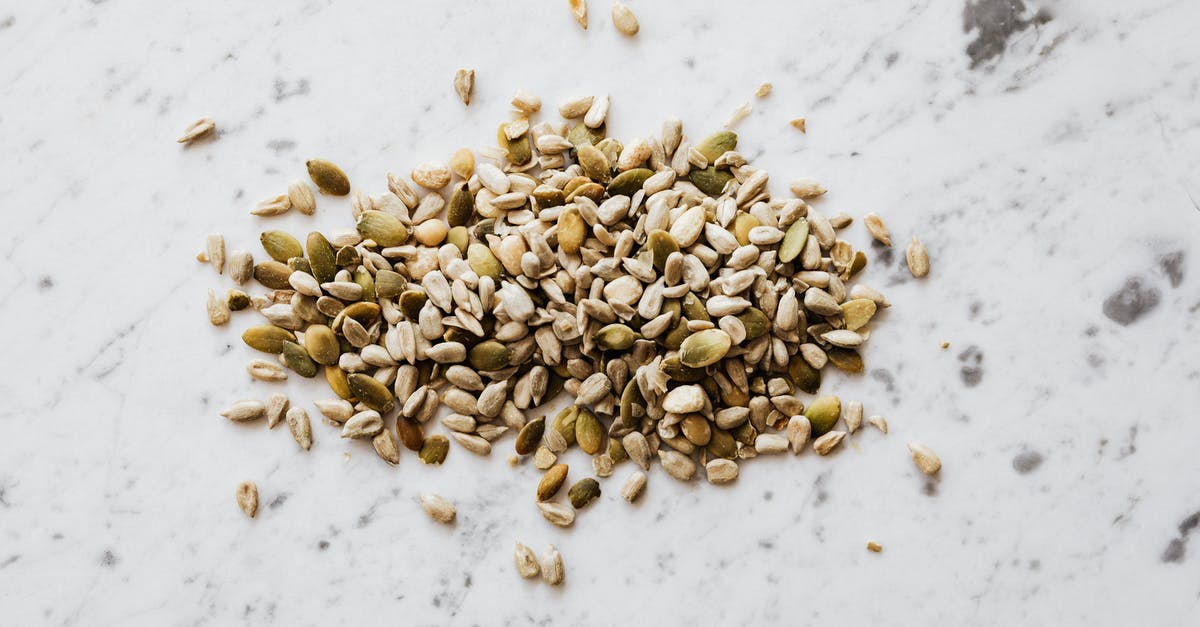 Do you de-hull seeds when making pumpkin seed flour? - From above of oval shaped dried pumpkin seeds with green and gray shell spilled on marble surface with spots