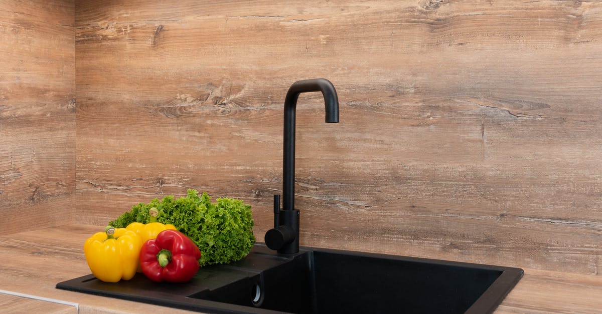 Do you have to wash frozen vegetables? - Fresh green lettuce with red and yellow bell peppers placed near sink on wooden tabletop in modern kitchen