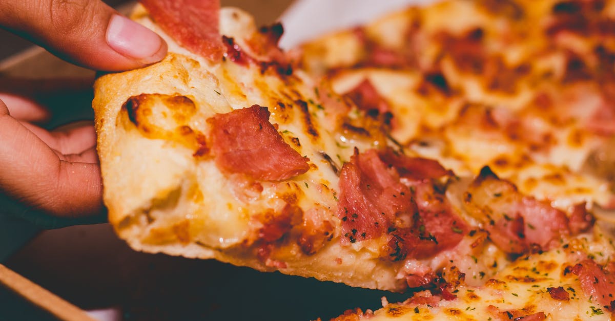 Doctoring up part-skim low-moisture mozzarella for pizza - Close-Up Photo of Person Holding Pizza