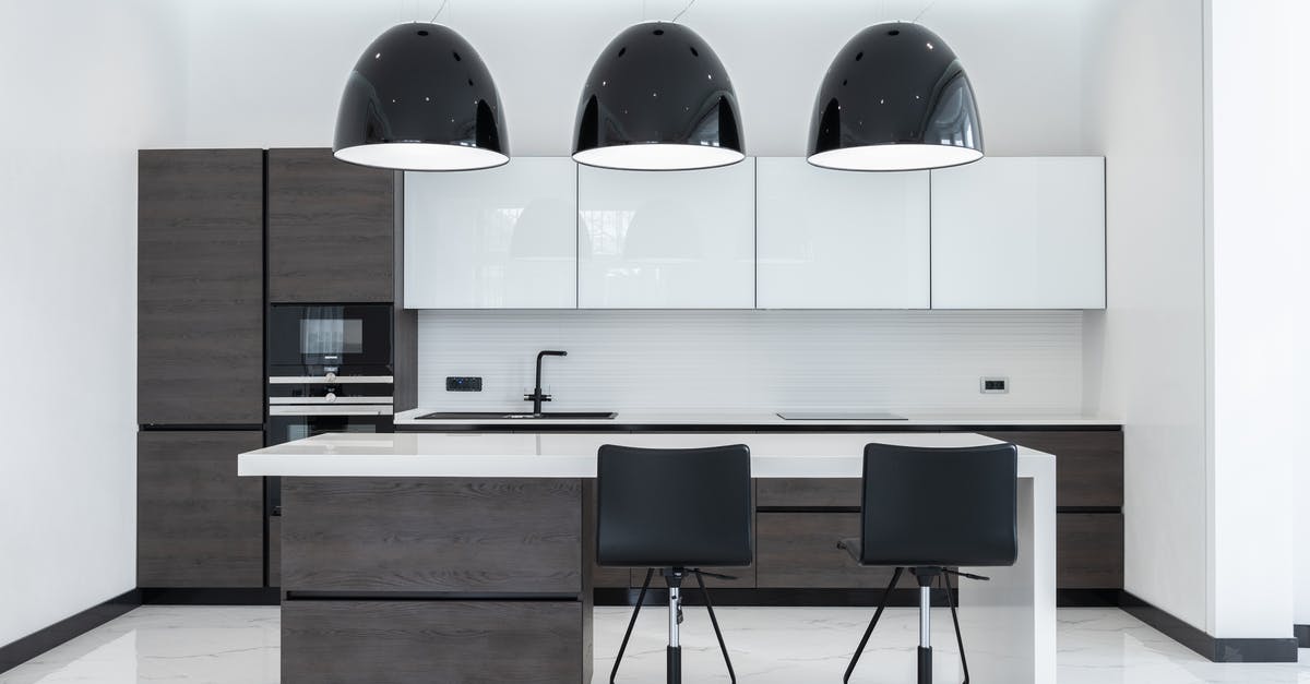 Does a home produce refrigerator exist? - Creative lamps hanging over table with chairs in spacious kitchen with modern furniture and appliances