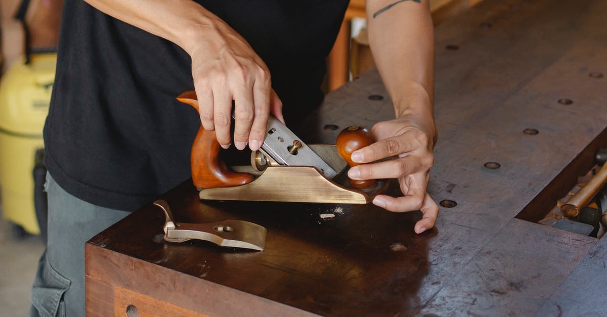 Does a silicone cutting board really work well? - Anonymous male carpenter with tattoo adjusting knife in planer for cutting wood during work in professional workshop on blurred background