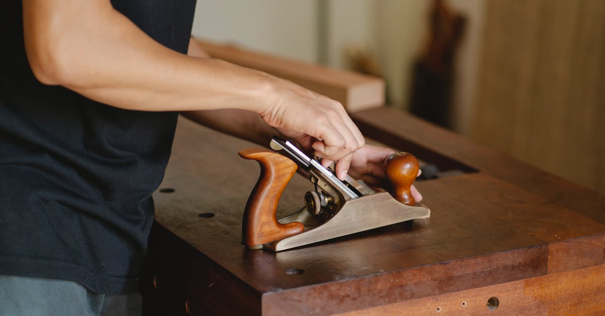 Does a silicone cutting board really work well? - Side view of unrecognizable male carpenter changing knife in planer while cutting piece of board in studio on blurred background