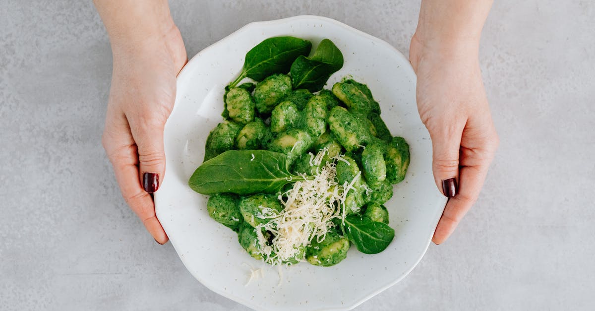 Does a strong smell when cooking spinach indicate anything? - A Woman Holding a Plate of Gnocchi