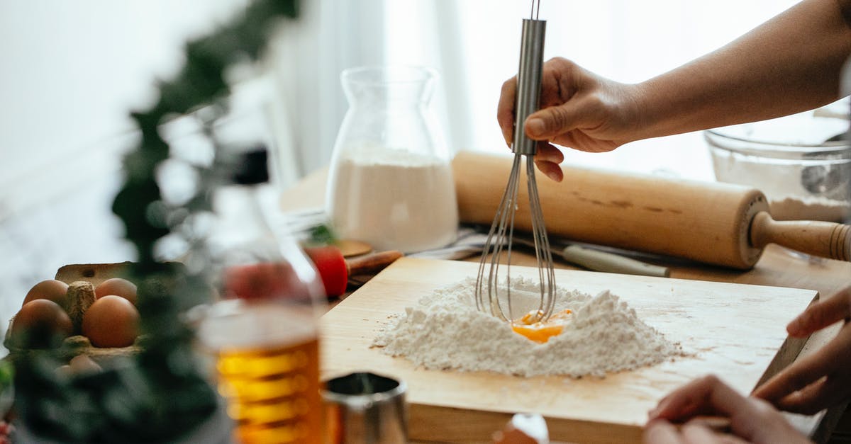 Does adding flour before egg coating and breadcrumbs help sticking? - Crop unrecognizable ladies standing near table and whipping flour with egg for recipe on cutting board at home