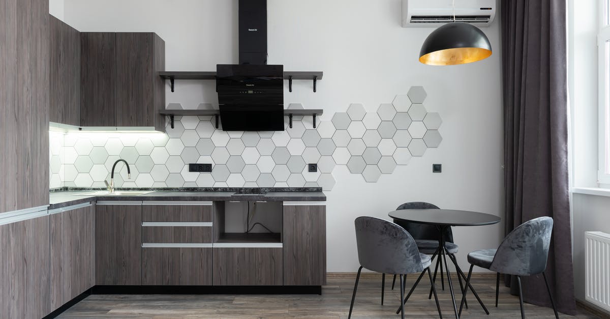 Does an activated carbon filter in a kitchen hood dry the air? - Creative design of kitchen with cupboards and cabinets under hood against table with chairs in daylight at home Does an activated carbon filter in a kitchen hood dry the air? - Creative design of kitchen with cupboards and cabinets under hood against table with chairs in daylight at home