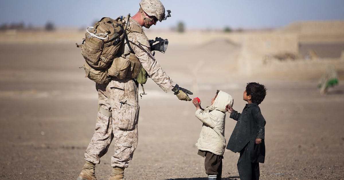 Does anyone know what kind of pan this is? - Soldier Giving Red Fruit on 2 Children during Daytime