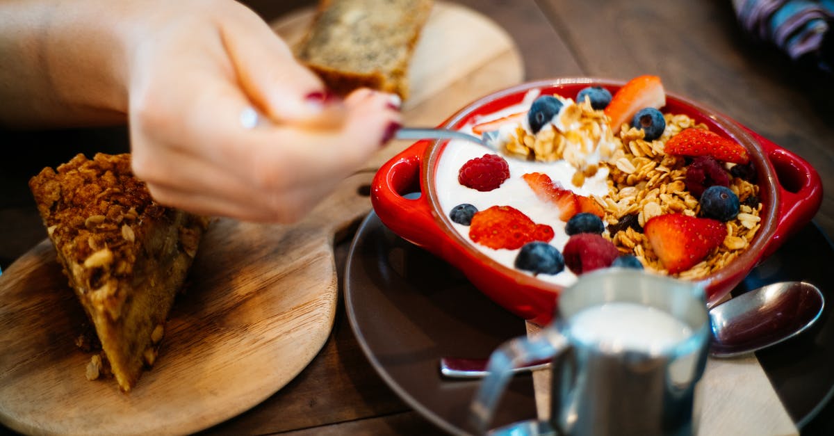 Does breadmaker bread need to include milk powder? - Person Holding Spoon and Round Red Ceramic Bowl With Pastries