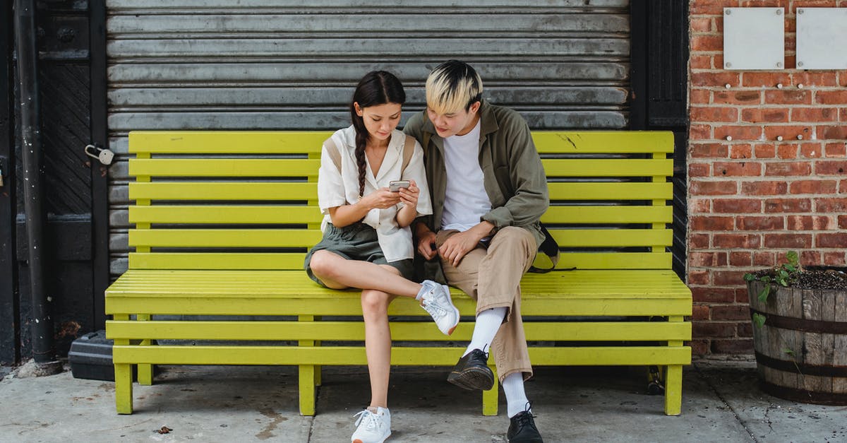 Does Domino's use rennet-free cheese? - Serious multiracial couple resting on yellow bench and browsing smartphone and looking at screen