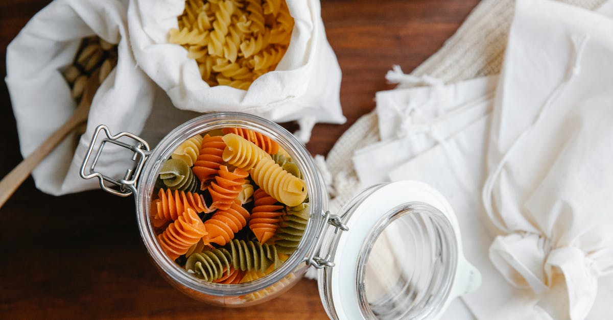 Does dry pasta need washing? - Top view of colorful rotini in opened glass jar and fusilli in white bags near empty recycling white bags on table