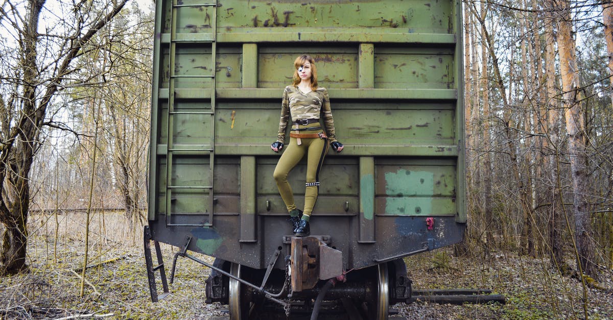 Does invisible mould exist? - Slim woman wearing modern camouflage outfit with eye patch standing on aged green train in woods