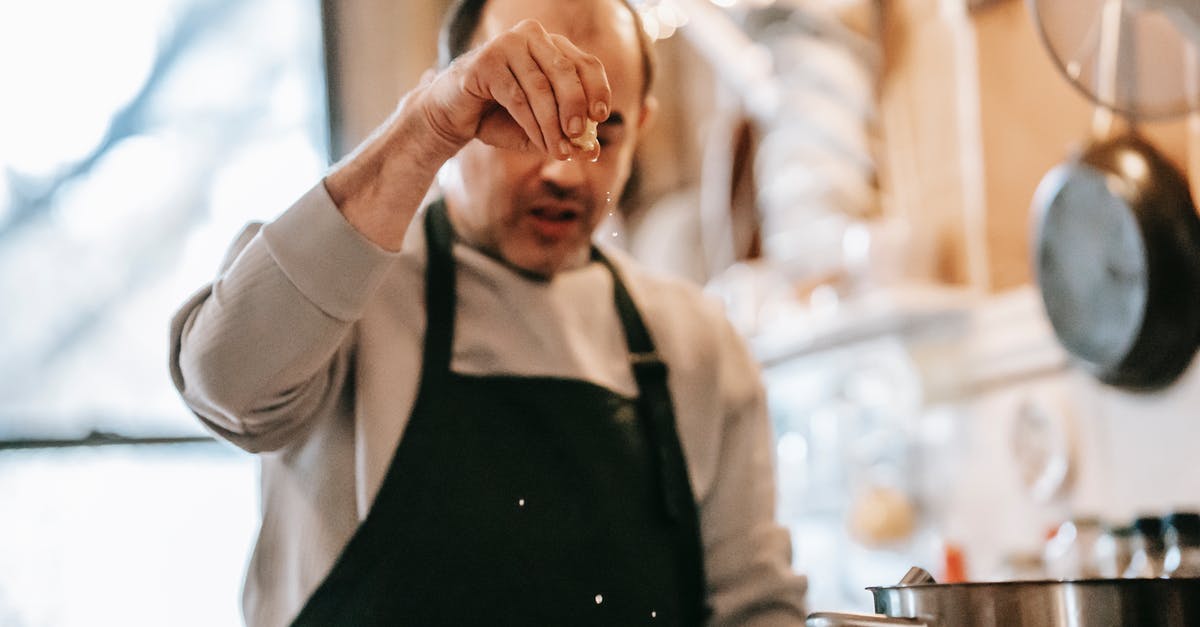 Does it matter when you add the salt? [duplicate] - Concentrated middle aged ethnic male in casual clothes and apron adding salt while preparing delicious dish in kitchen at home