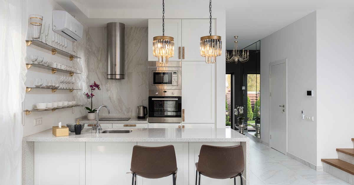 Does ketchup belong in the fridge, or the cupboard? - Interior of contemporary kitchen with modern appliances and chairs at white counter near  wall with shelves in spacious apartment near stairs