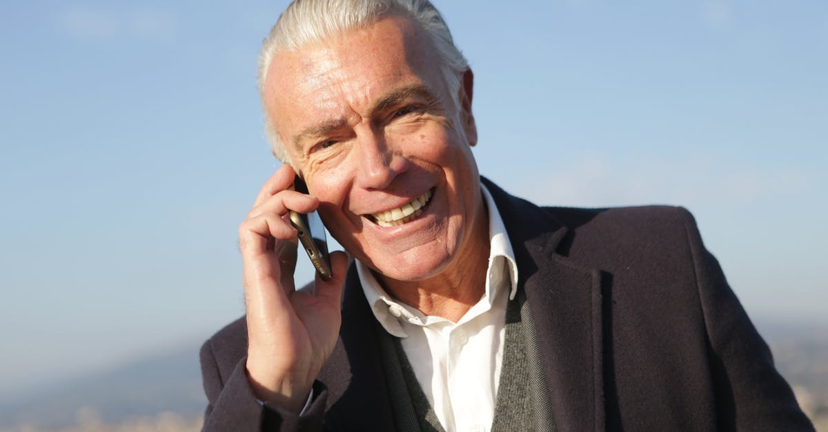 Does liver reheat well? - Delighted male entrepreneur wearing classy jacket standing in city and making phone call while smiling and looking at camera