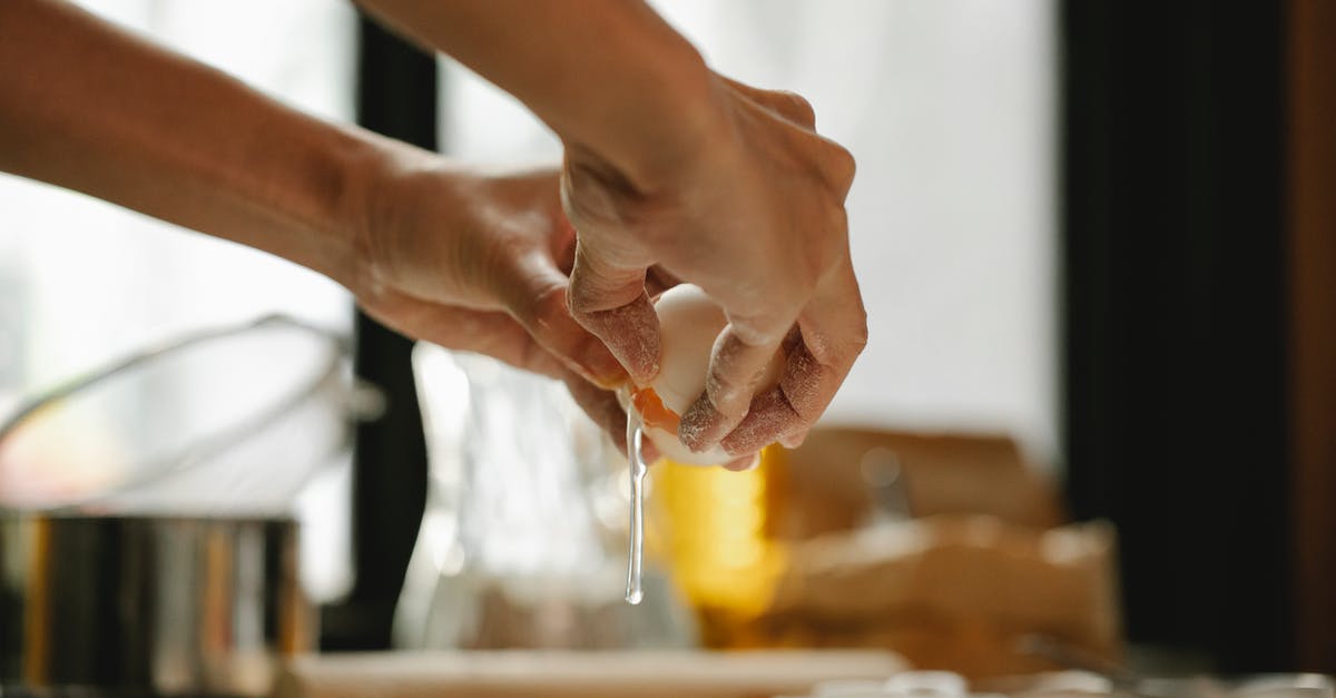 Does multi-cooker actually bake? - Unrecognizable woman cracking egg into flour on table making dough in kitchen on blurred background