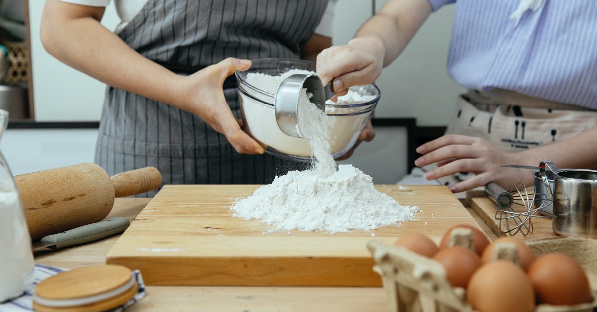 Does multi-cooker actually bake? - Crop anonymous woman in apron and young lady standing near counter and pouring flour on wooden cutting board in modern kitchen