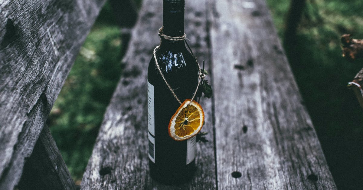 Does oak aged wine contain vanillin? - From above of glass bottle of wine with dried orange placed on old wooden bench in nature in daytime