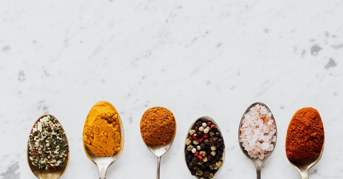 Does placement of ingredients and condiments on a sandwich change the taste? - Top view of assorted aromatic condiments arranged together in metal spoons on marble surface used for delicious gourmet meal cooking