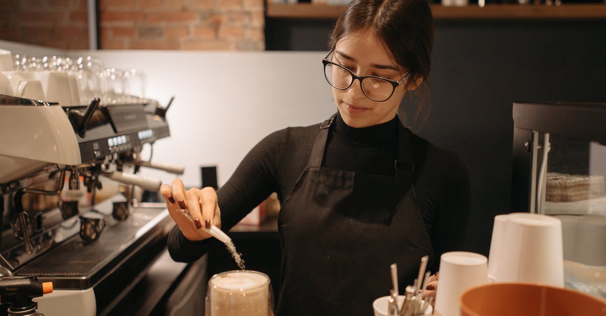 Does putting salt in coffee really remove bitterness? - A Woman Pouring a Sachet of Sugar in a Glass of Coffee at the Counter