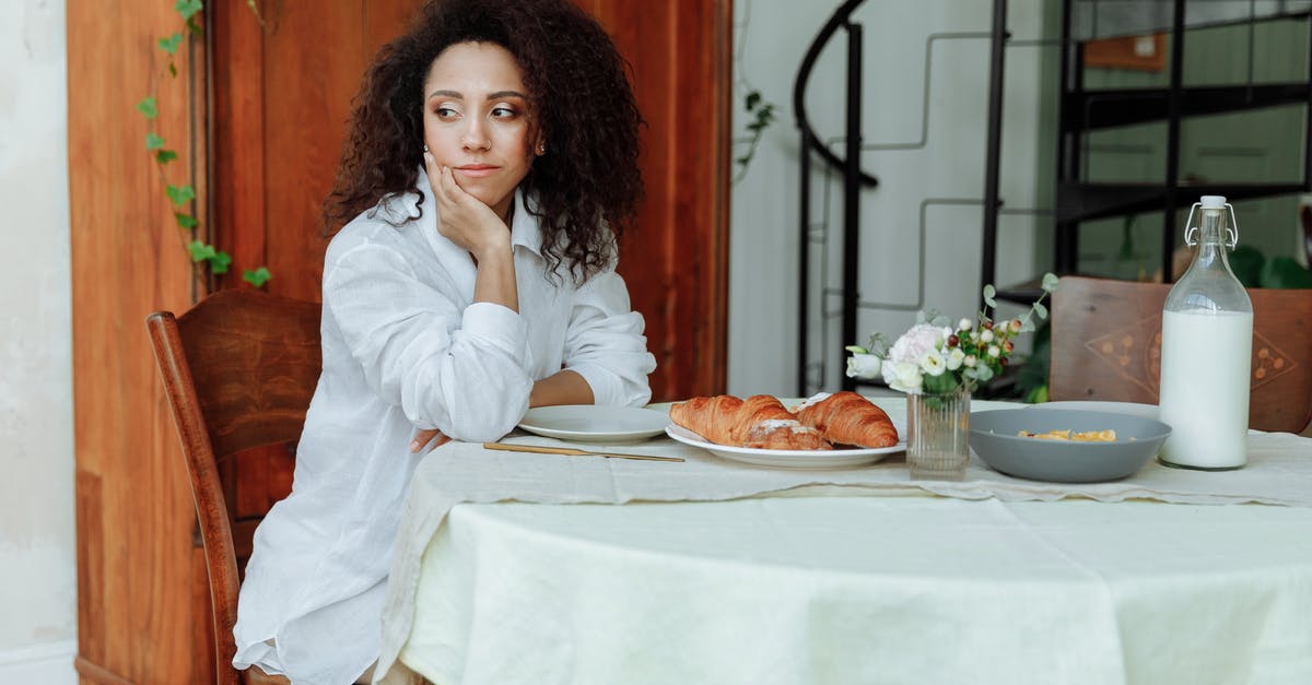 Does "American" Food exist around the world? - Woman with Curly Hair Sitting Near a Plate of Croissants