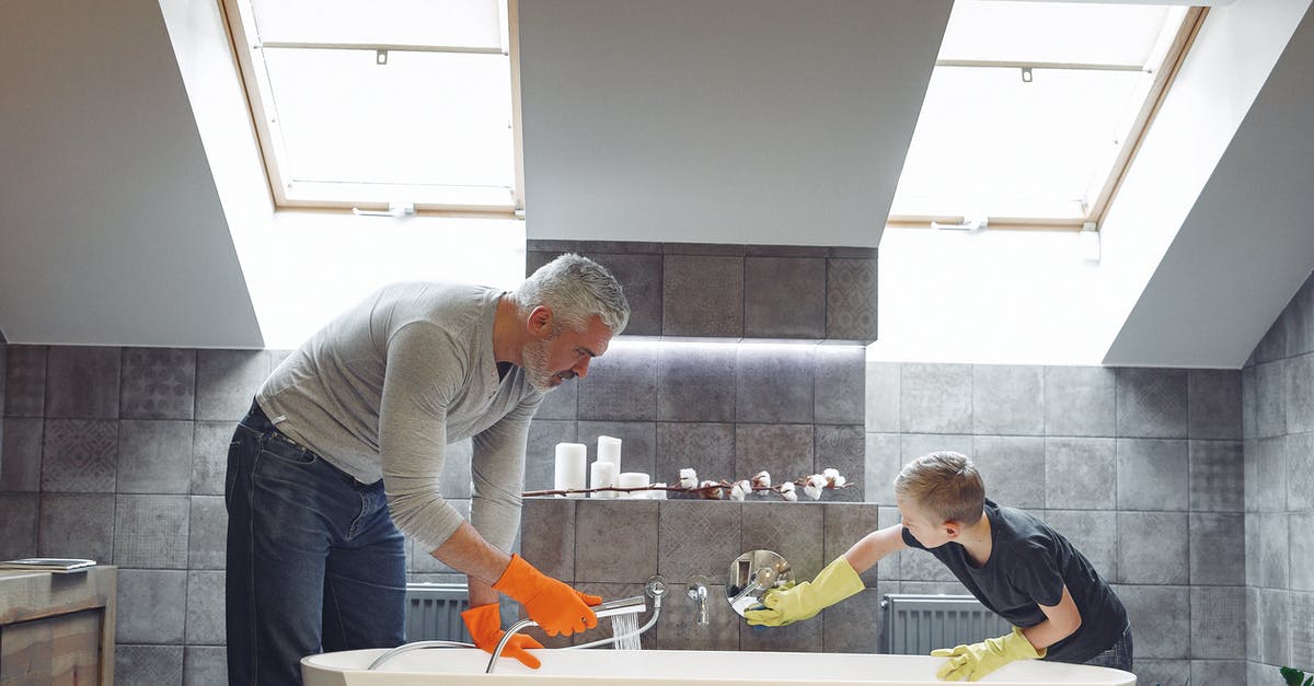 Does soaking in saltwater for 20 mins help cleanse mussels? - Side view of grey haired dad with beard in orange rubber gloves cleaning bathroom together with son