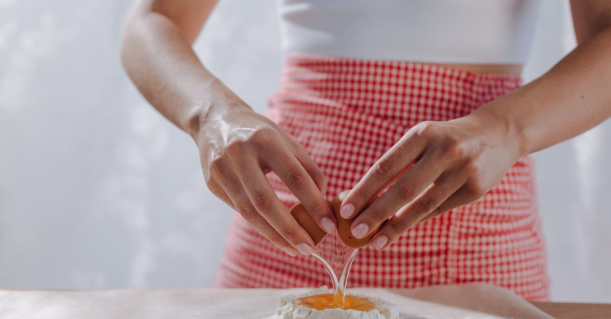 Does the addition of acid into flour inhibit gluten formation? - Unrecognizable Female Hands Breaking Egg into Mound of Flour