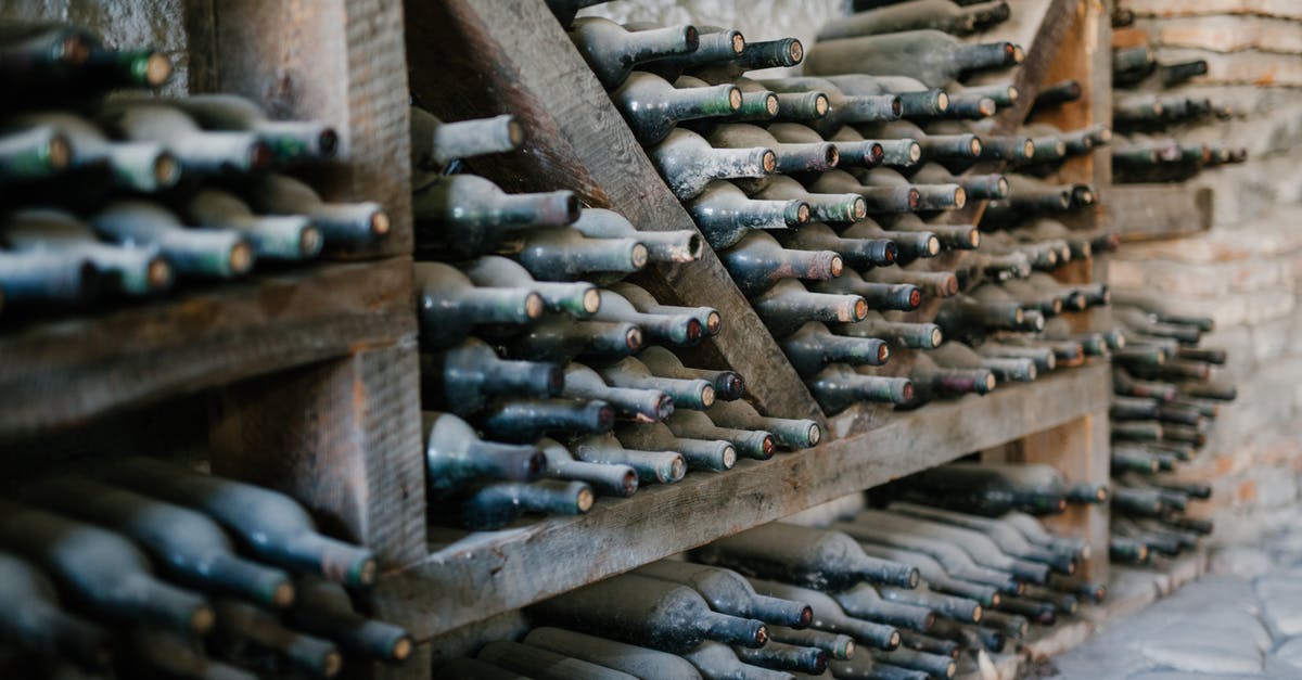 Does the vendors’ storage method affect shellfish quality? - Dusty alcoholic beverage bottles with coiled corks on wooden shelves at wine farm