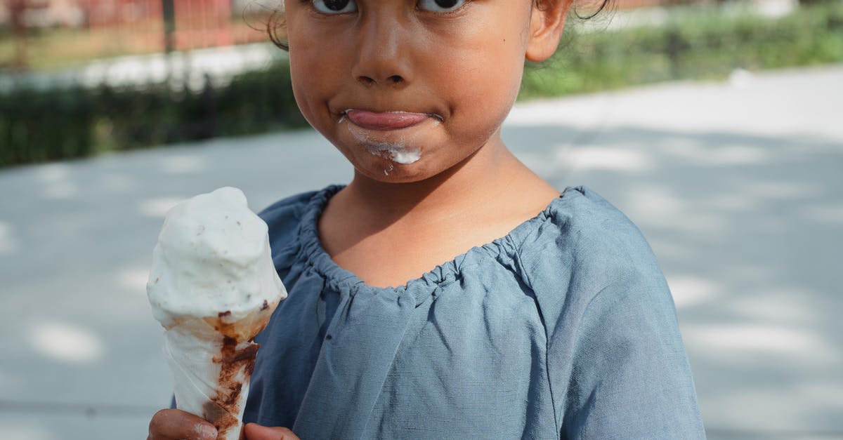 Does vanilla really bring out the flavour of other foods? - Crop adorable little Asian girl in casual clothes eating ice cream and looking at camera