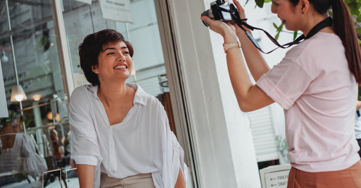 Does wear and tear limit the usefulness of a Dutch oven? - Crop Asian lady in casual wear taking photo of charming best friend on camera near glass wall in city