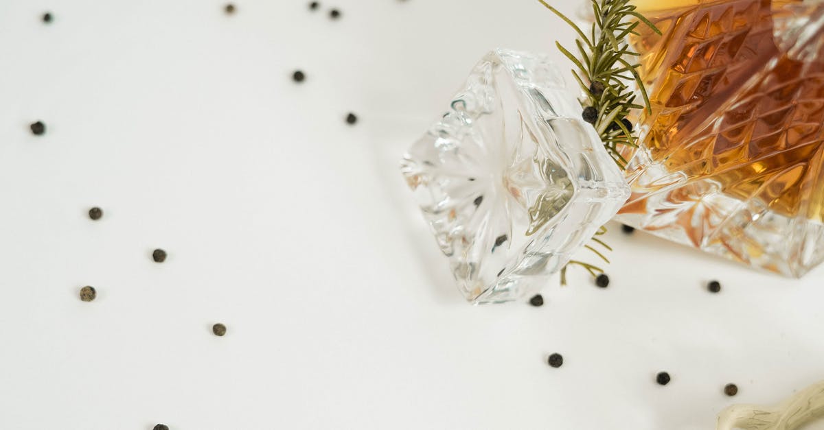 Does wrapping a bottle of whisky in plastic affect the taste? - From above of glass carafe filled with Scotch whiskey placed on white background with rosemary twig and scattered back peppercorns