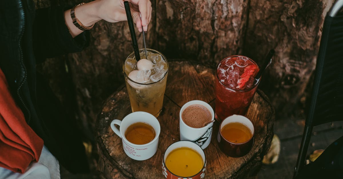 Donvier Ice Cream Maker - why stirring only every 2 minutes? -  A Person Stirring a Cold Beverage on a Wooden Table with Assorted Drinks