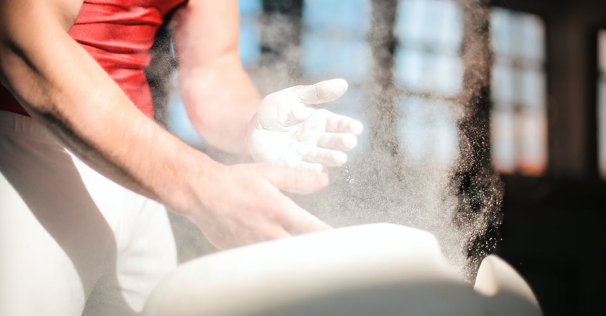 Dry rub duration - Crop male gymnast in sportswear rubbing hands with dry spots magnesium powder while preparing for exercises