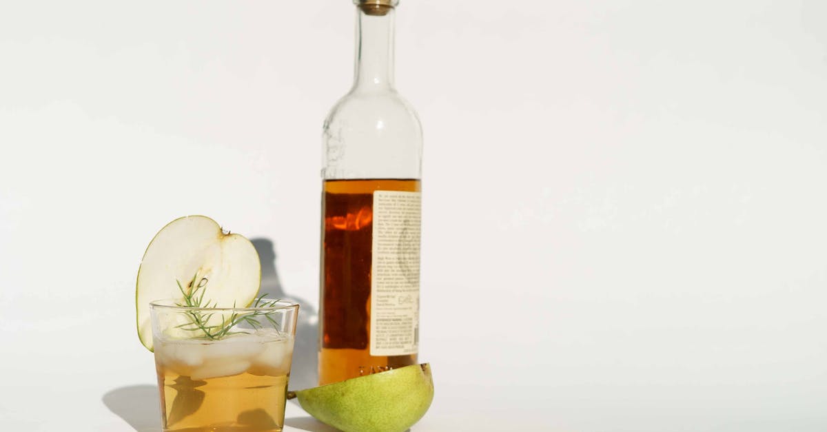 Earthy tasting frozen salmon - Glass bottle of calvados with halved pear and rosemary sprigs placed on white background