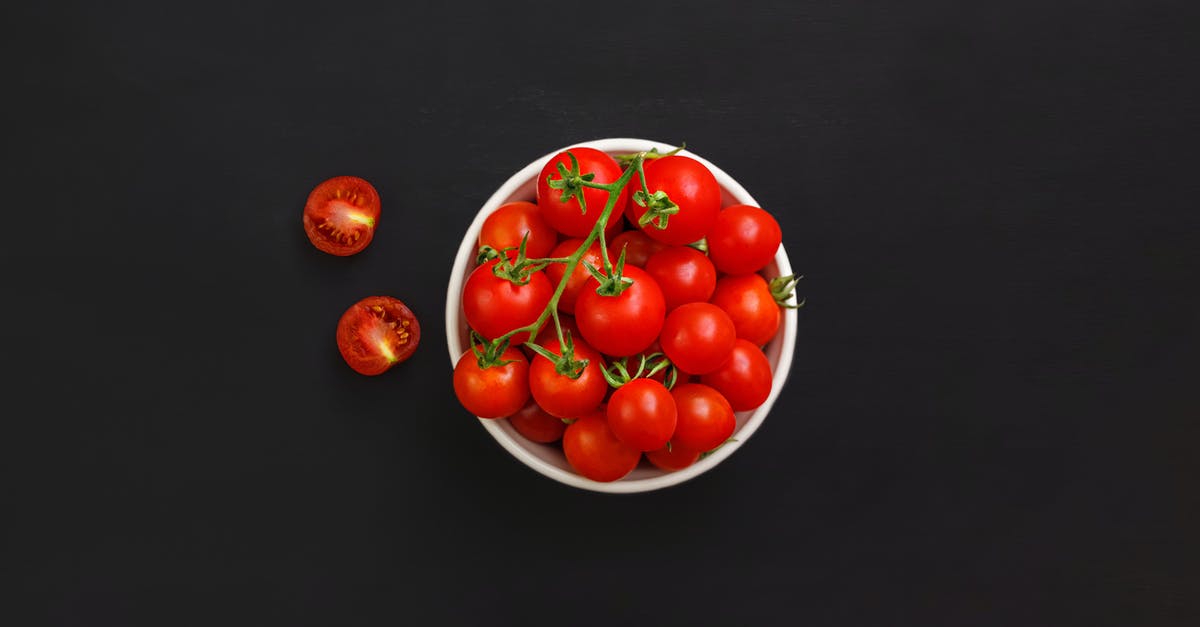 Eating dehydrated uncooked red potato - Bowl with ripe cherry tomatoes on black background