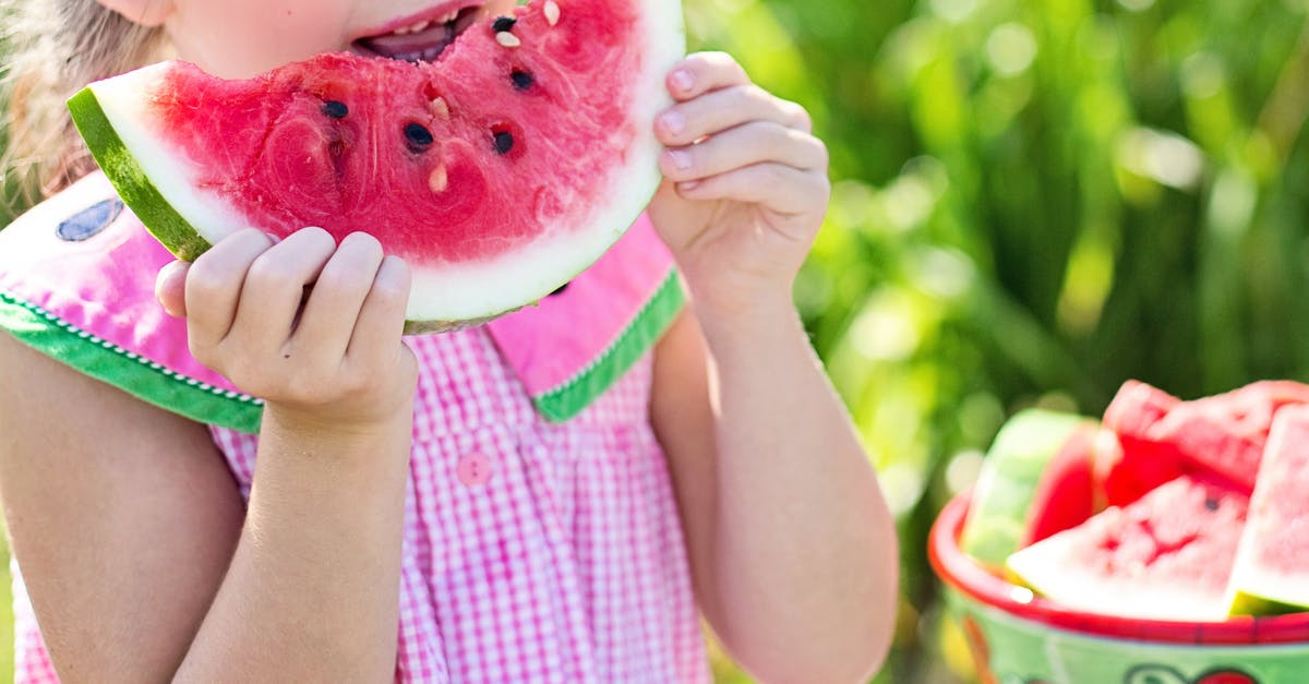 Eating dehydrated uncooked red potato - Girl Eating Sliced Watermelon Fruit Beside Table