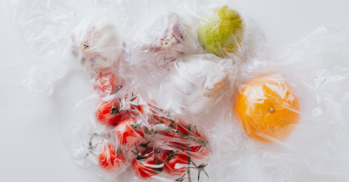 Edible straws that look like plastic ones - From above of bunch of ripe tomatoes put near garlic bulbs and citrus fruits covered with transparent plastic bags on white surface