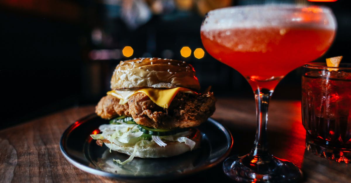 Effect of ethanol concentration on bread flavor - Appetizing hamburger with fried meat and lettuce served on wooden table with red alcoholic drink in modern cafe on blurred background