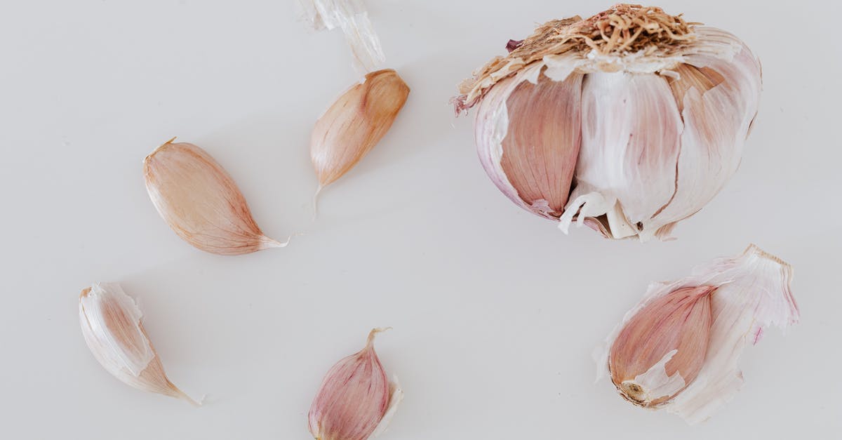 Efficient method to peel raw potatoes - Top view of process separation of garlic cloves before cooking placed on gray background