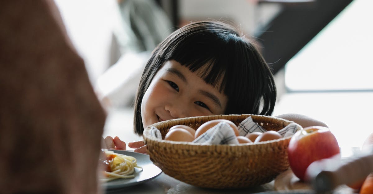 Egg safety. When to eat and when to not eat - Happy Asian little girl in kitchen