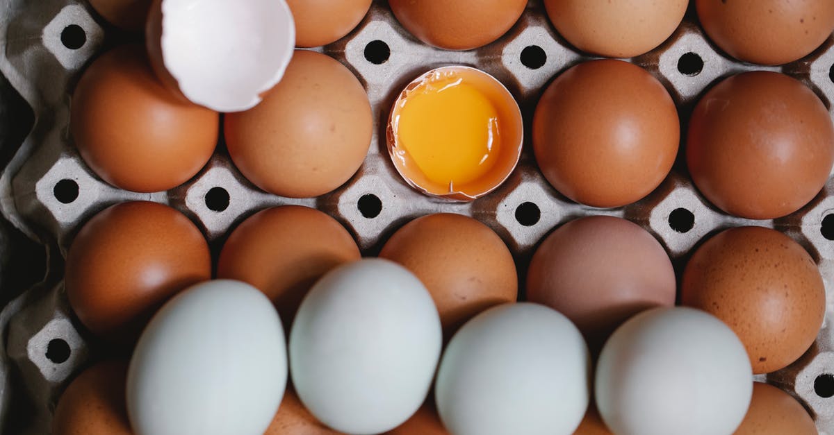 Egg yolk substitute for whole eggs in strata - Top view of yolk in broken eggshell among whole eggs in carton container