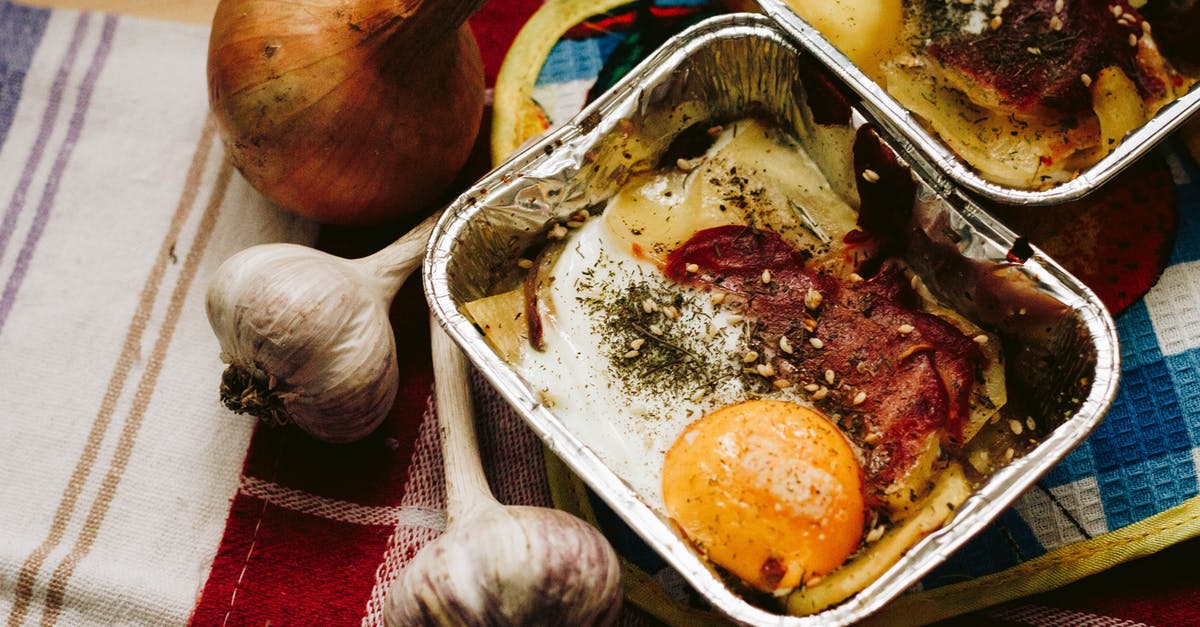 Eggs sticking to the pan - Cooked Food in Square Grey Tray Beside Garlics and Onion