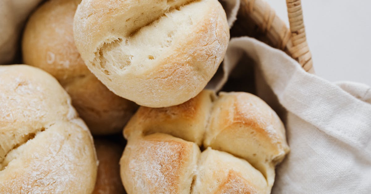 egg-wash role in having soft bread buns - From above closeup of freshly baked delicious buns with cross cuts on top lying on linen towel in wicker bowl