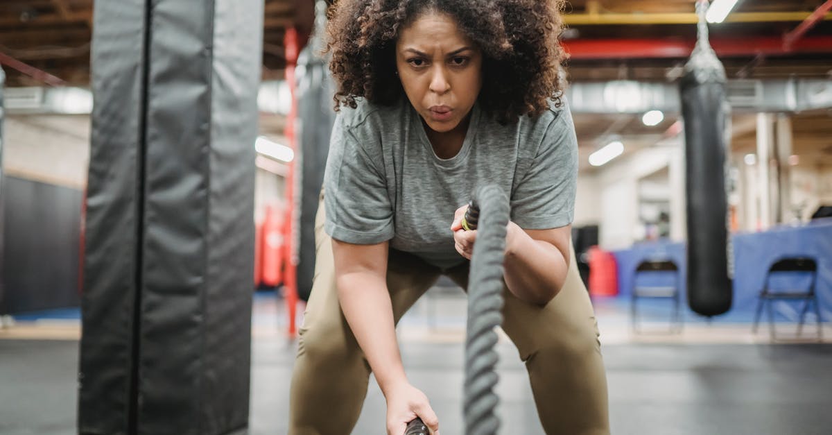 Equipment: Intense candle for nabemono. What is it? - Determined black woman exercising with battle ropes in gym