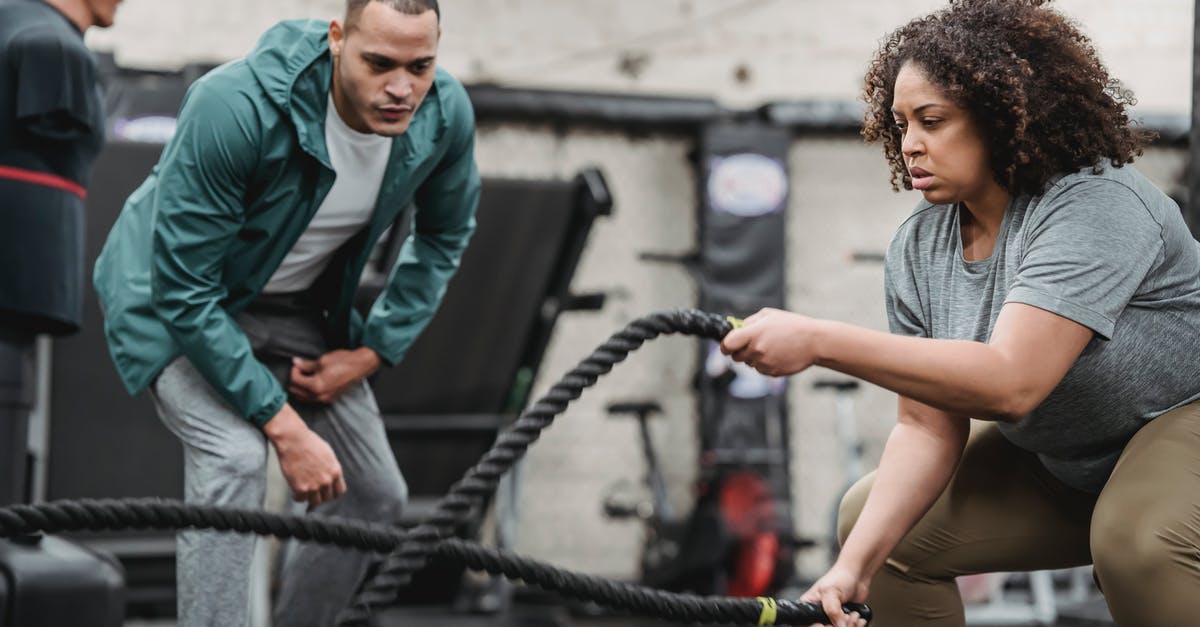 Equipment: Intense candle for nabemono. What is it? - Plus sized African American female in sportswear exercising with battle ropes near serious male instructor during intense workout in modern fitness center