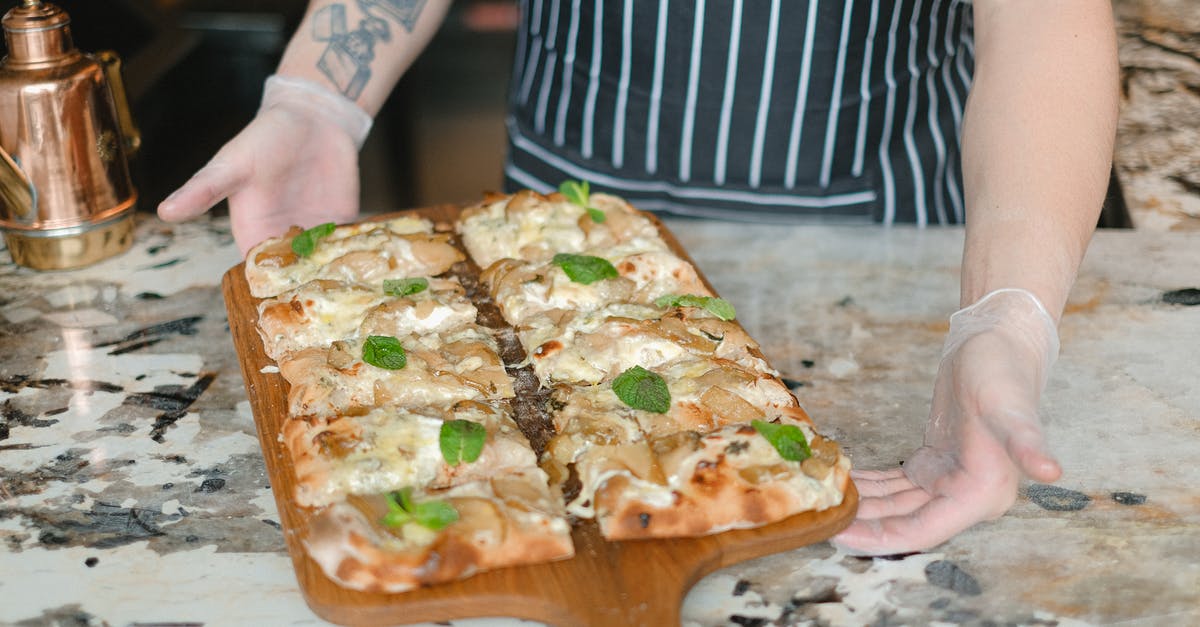 Excess oil / holes in cheese when baking pizza - A Person Holding a Tray Pizza With Mint Leaves Toppings