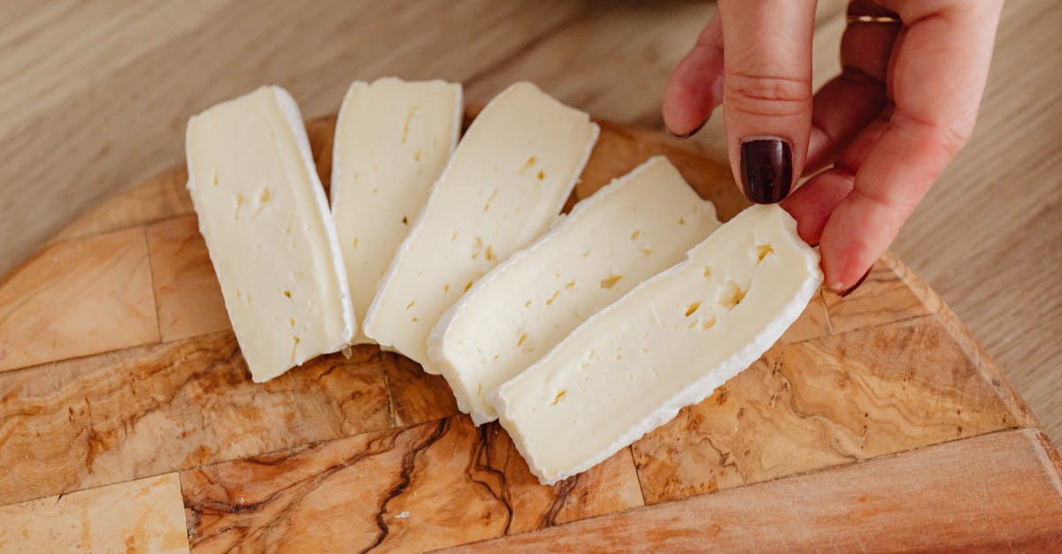 Extra built up mold on brie cheese - Person Holding White Cheese on Brown Wooden Chopping Board