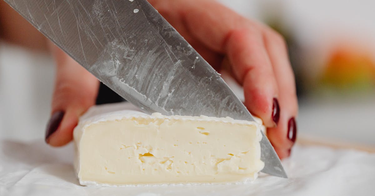 Extra built up mold on brie cheese - Hands of a Woman Slicing White Cheese