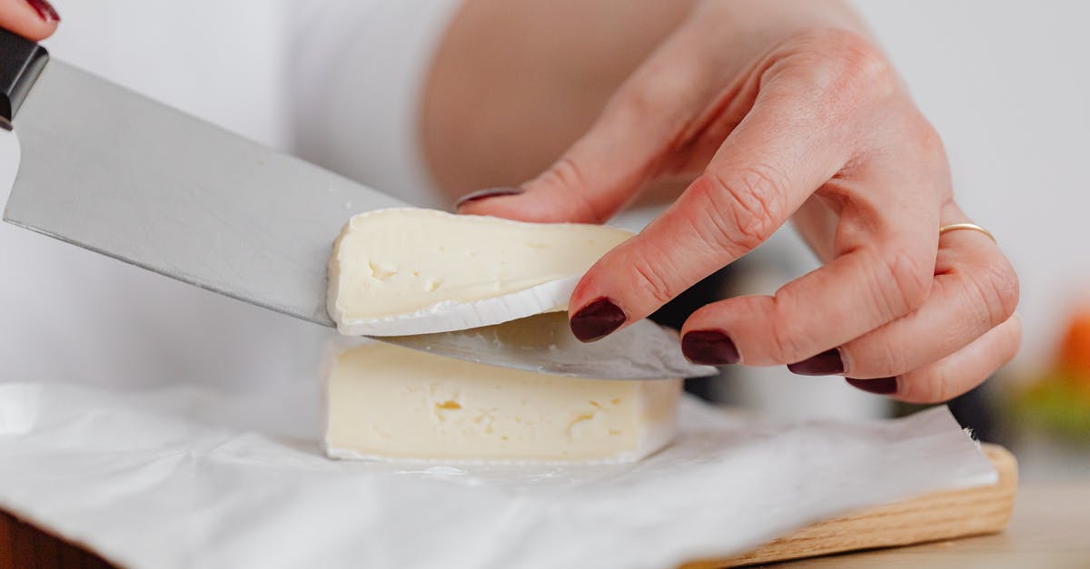 Extra built up mold on brie cheese - Hands of a Person Slicing Cheese