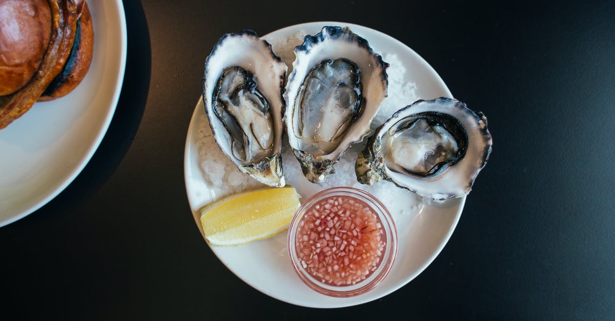 Extracting flavor from lemon zest - Top view of sophisticated seafood dish with oysters served on plate with sauce and lemon on table in modern restaurant